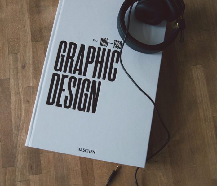 Discover graphic design history with this book and headphones on a wooden floor.